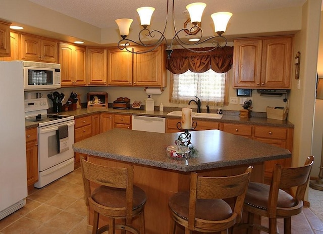 kitchen with white appliances, a breakfast bar area, a kitchen island, an inviting chandelier, and a sink