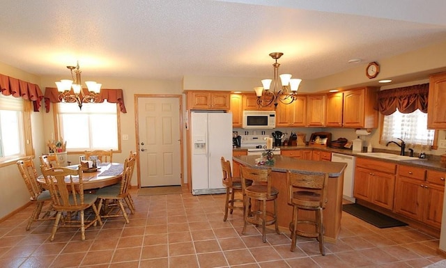 kitchen featuring a sink, white appliances, a center island, and a chandelier