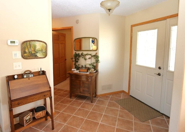 entryway with light tile patterned floors, visible vents, a textured ceiling, and baseboards