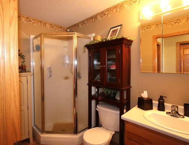 bathroom with toilet, a stall shower, vanity, and a textured ceiling