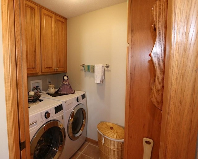 clothes washing area with cabinet space, tile patterned flooring, and washing machine and clothes dryer