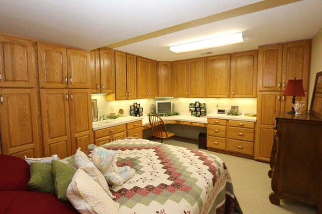 kitchen featuring light countertops, brown cabinetry, light colored carpet, and built in study area