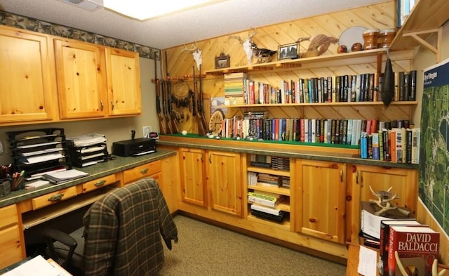 office space featuring built in desk, visible vents, a textured ceiling, and wooden walls