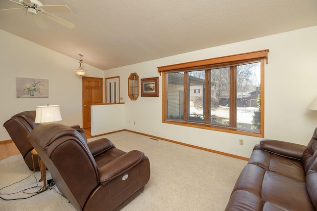 living area featuring baseboards, ceiling fan, vaulted ceiling, a textured ceiling, and light carpet