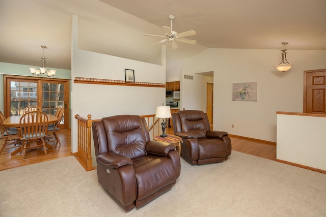 living room featuring lofted ceiling, ceiling fan with notable chandelier, baseboards, and light carpet