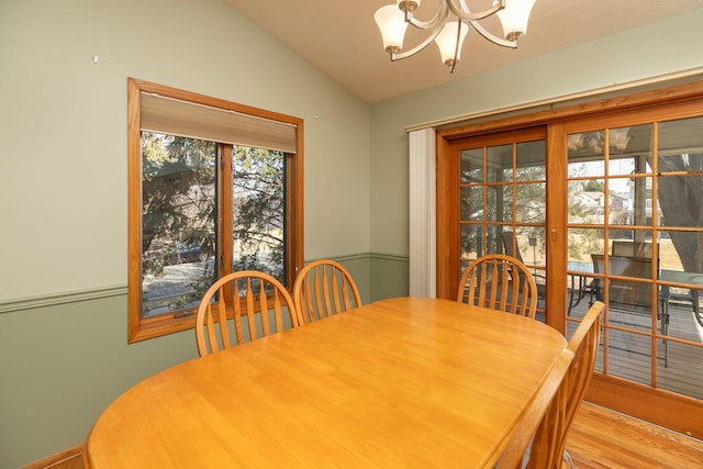 dining room with vaulted ceiling, a notable chandelier, and wood finished floors