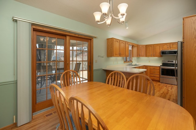 dining area with lofted ceiling, visible vents, light wood finished floors, and a chandelier