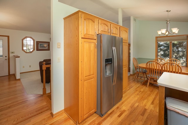 kitchen with decorative light fixtures, vaulted ceiling, light wood-style flooring, stainless steel refrigerator with ice dispenser, and a notable chandelier