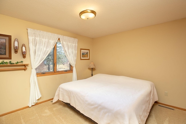 bedroom featuring light carpet, a textured ceiling, and baseboards