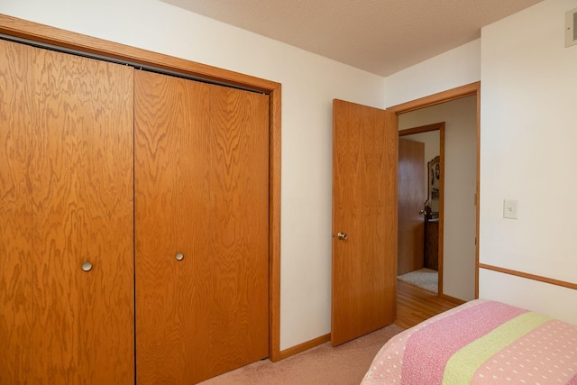 bedroom featuring baseboards, visible vents, a closet, and light carpet