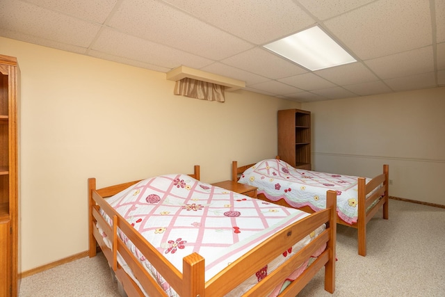 carpeted bedroom featuring a paneled ceiling and baseboards