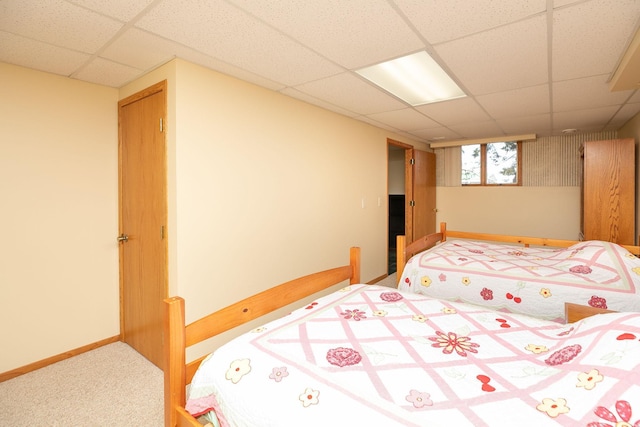 bedroom with carpet flooring, a paneled ceiling, and baseboards