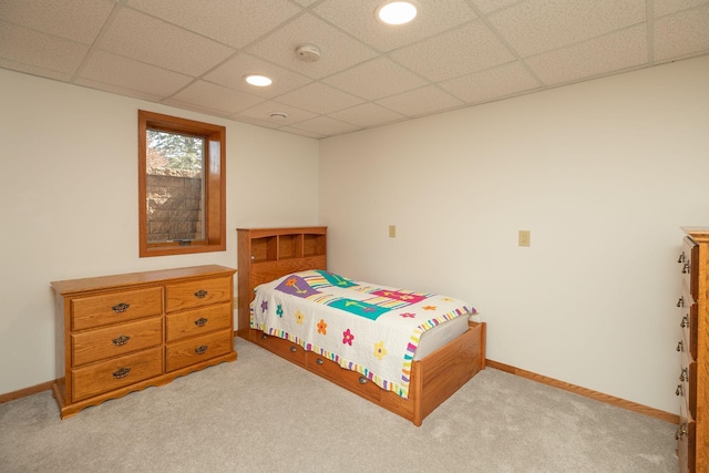 bedroom featuring light colored carpet, a paneled ceiling, and baseboards