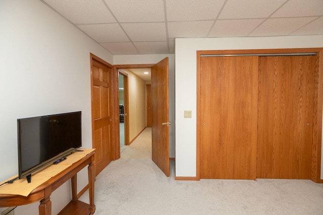 interior space with a drop ceiling, a closet, light carpet, and baseboards