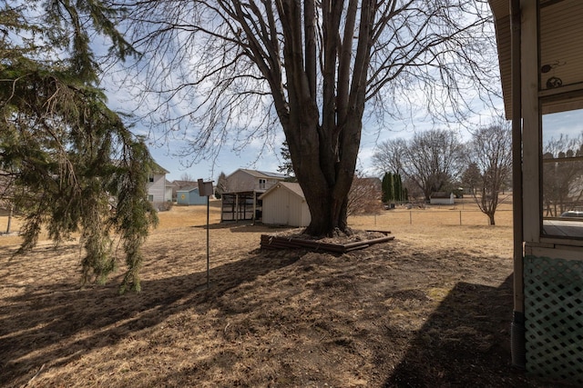 view of yard featuring fence, an outdoor structure, and a shed