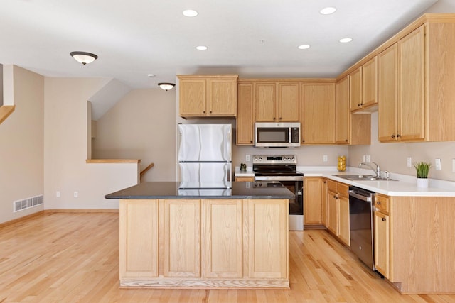 kitchen featuring light brown cabinetry, visible vents, appliances with stainless steel finishes, and a sink