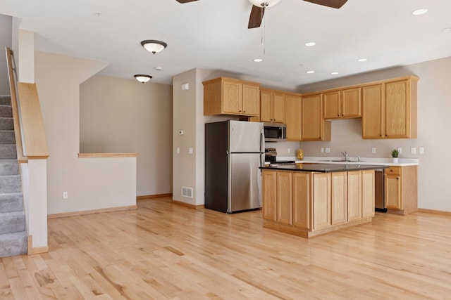 kitchen featuring visible vents, a ceiling fan, a sink, stainless steel appliances, and light wood-style floors