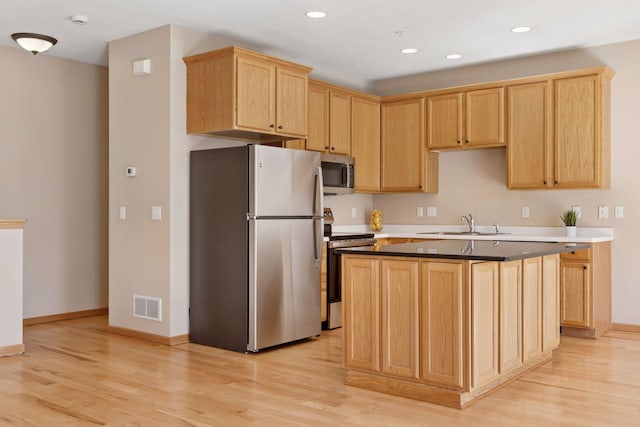 kitchen with visible vents, light brown cabinetry, a sink, appliances with stainless steel finishes, and light wood-type flooring