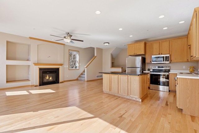 kitchen with recessed lighting, light wood-type flooring, a kitchen island, and appliances with stainless steel finishes