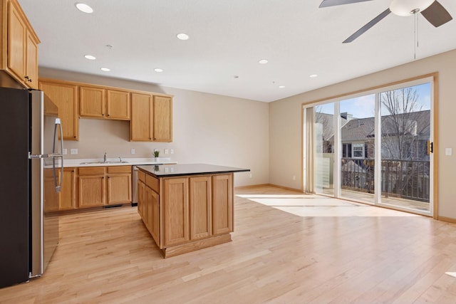 kitchen featuring a kitchen island, recessed lighting, freestanding refrigerator, a sink, and light wood-type flooring