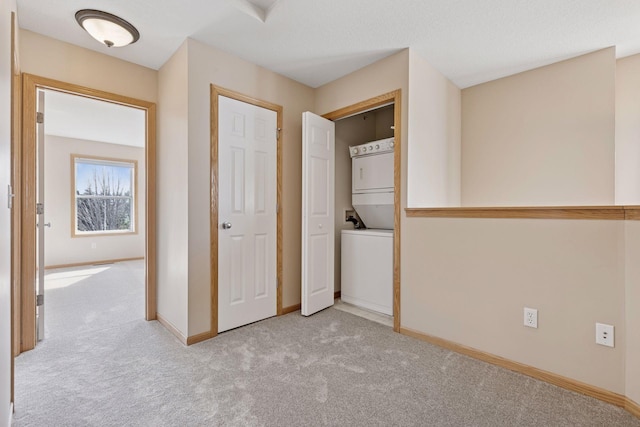 interior space with laundry area, carpet flooring, baseboards, and stacked washer and dryer