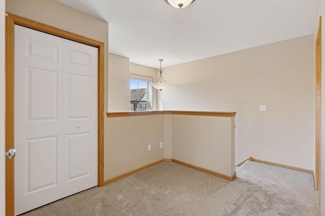 unfurnished room featuring carpet flooring, a textured ceiling, and baseboards