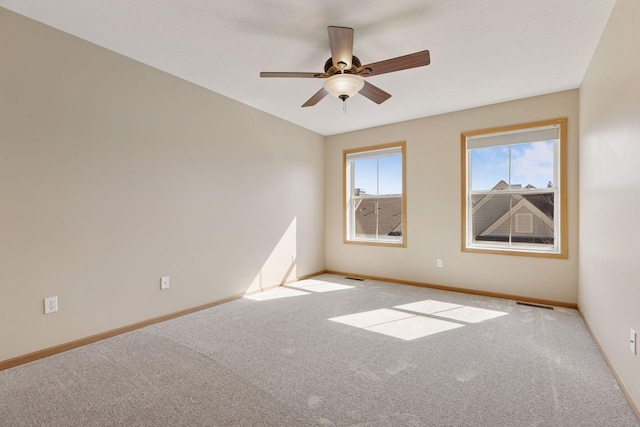 carpeted empty room with visible vents, baseboards, and a ceiling fan