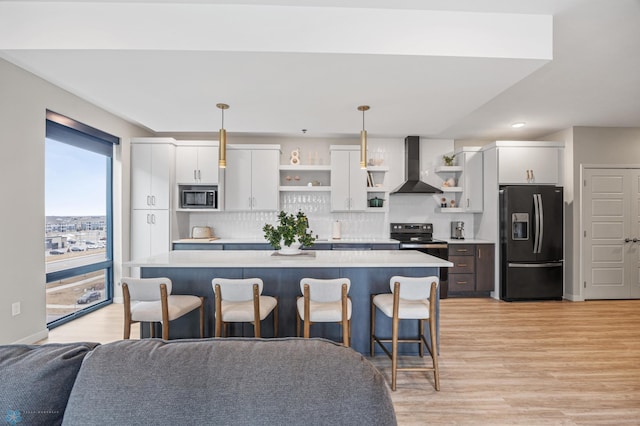 kitchen with stainless steel microwave, range with electric cooktop, black fridge with ice dispenser, wall chimney exhaust hood, and open shelves