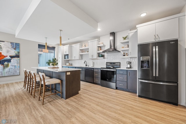 kitchen featuring open shelves, a center island, appliances with stainless steel finishes, wall chimney exhaust hood, and a sink