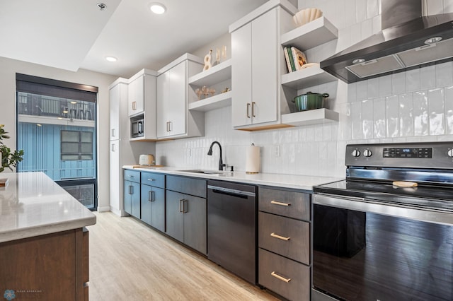 kitchen with open shelves, a sink, tasteful backsplash, appliances with stainless steel finishes, and wall chimney range hood