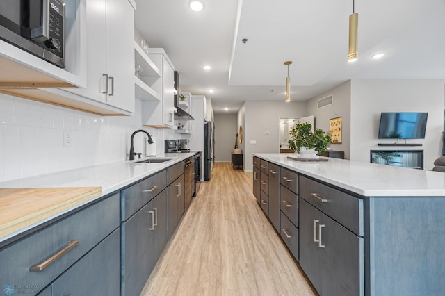 kitchen with a sink, open shelves, a center island, white cabinetry, and stainless steel appliances