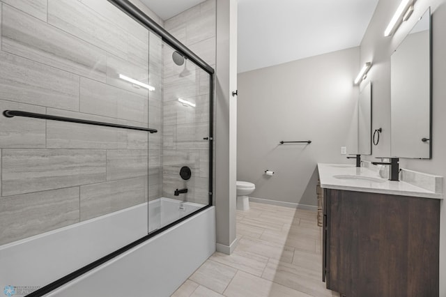 full bath featuring baseboards, bath / shower combo with glass door, toilet, and vanity