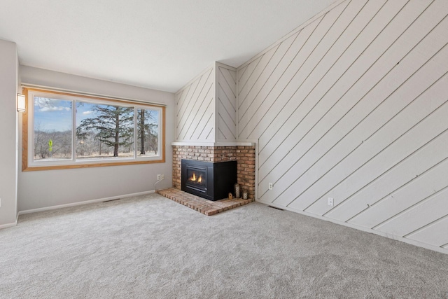 unfurnished living room with a brick fireplace, carpet flooring, and visible vents