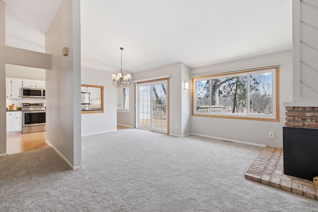 unfurnished living room featuring a chandelier, light colored carpet, and baseboards