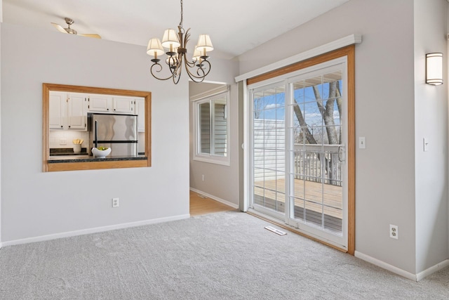 unfurnished dining area with carpet flooring, visible vents, baseboards, and an inviting chandelier