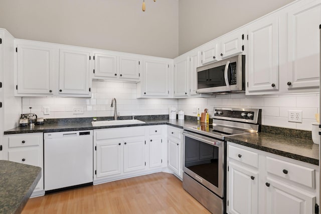 kitchen featuring light wood-style flooring, appliances with stainless steel finishes, white cabinets, and a sink