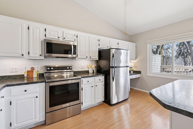 kitchen with stainless steel appliances, vaulted ceiling, white cabinetry, tasteful backsplash, and light wood-type flooring