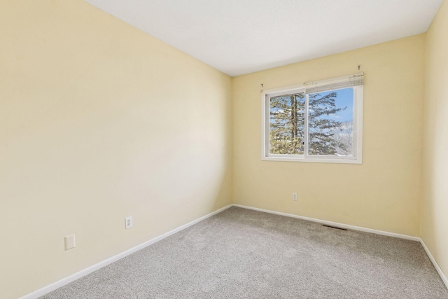 carpeted spare room featuring visible vents and baseboards