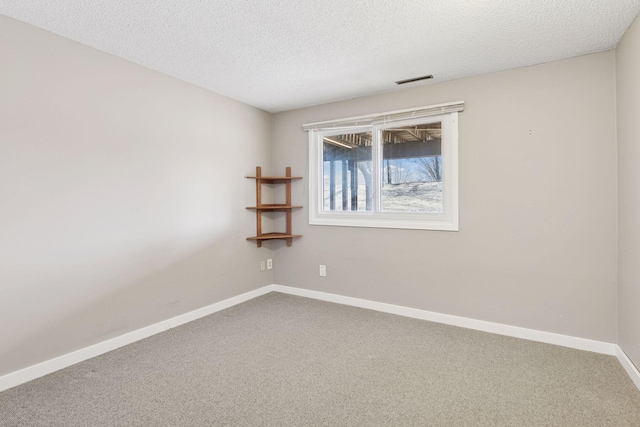 spare room with visible vents, carpet, baseboards, and a textured ceiling