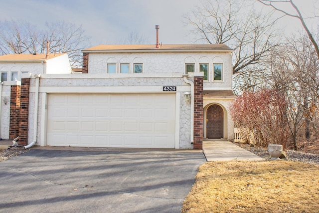 front of property featuring a garage, stucco siding, and aphalt driveway