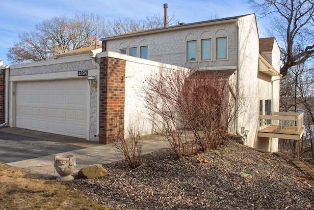 view of side of property featuring brick siding, a garage, and stucco siding