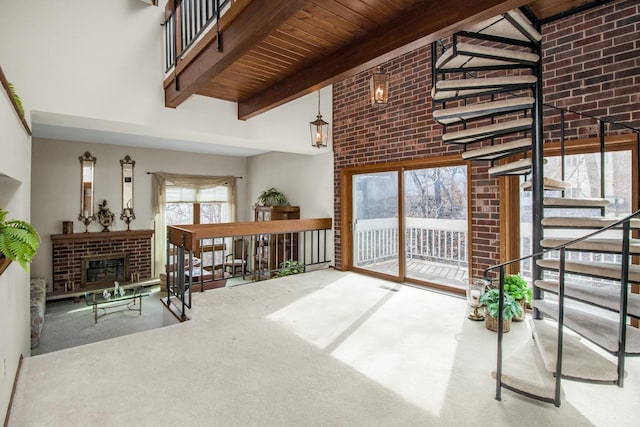 interior space featuring stairway, beam ceiling, a high ceiling, and a brick fireplace