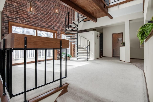 stairway featuring carpet flooring, beamed ceiling, brick wall, and a high ceiling