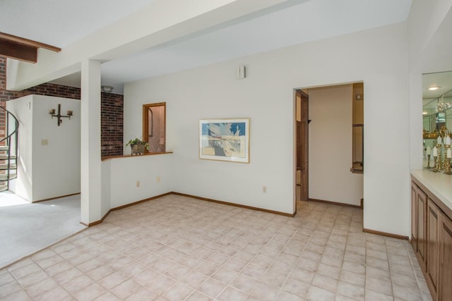 interior space featuring beam ceiling, light colored carpet, stairs, and baseboards