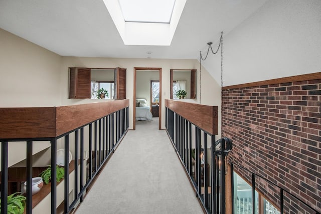 hall with light carpet, brick wall, and vaulted ceiling with skylight