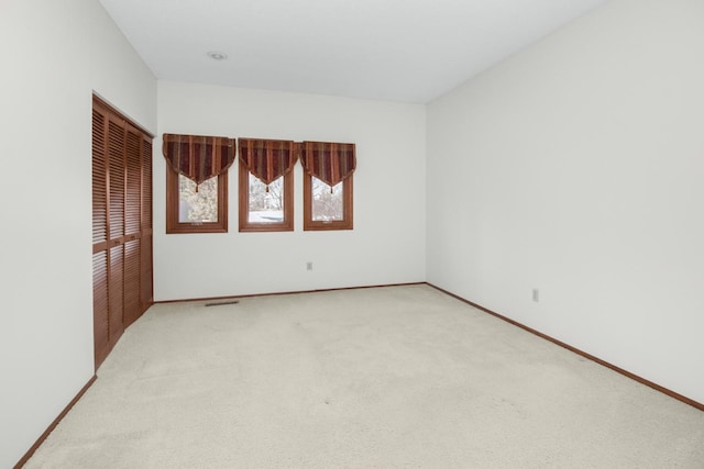 unfurnished room with baseboards and light carpet