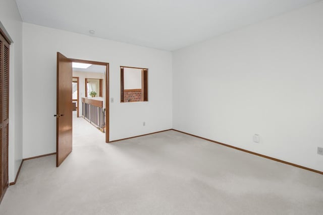 unfurnished room with baseboards and light carpet