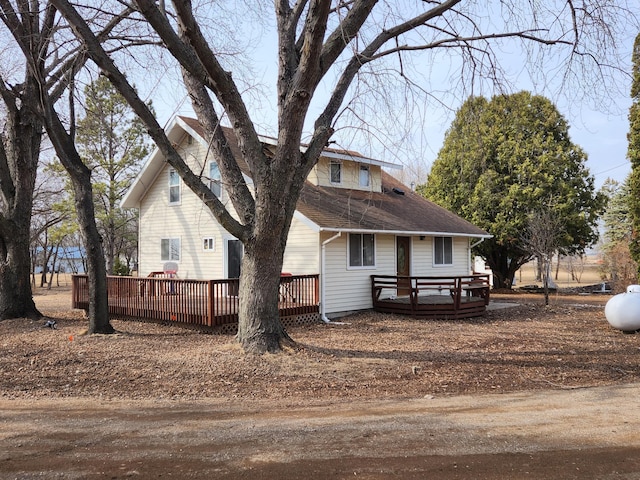 view of front facade featuring roof with shingles and a deck