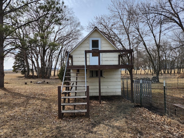 rear view of property featuring stairs and fence