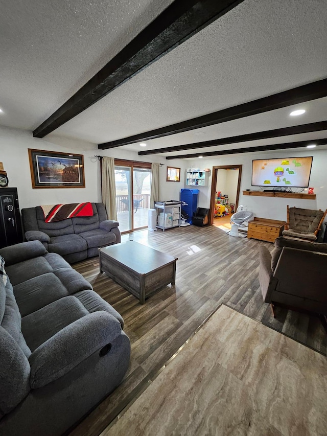 living room with beamed ceiling, a textured ceiling, and wood finished floors